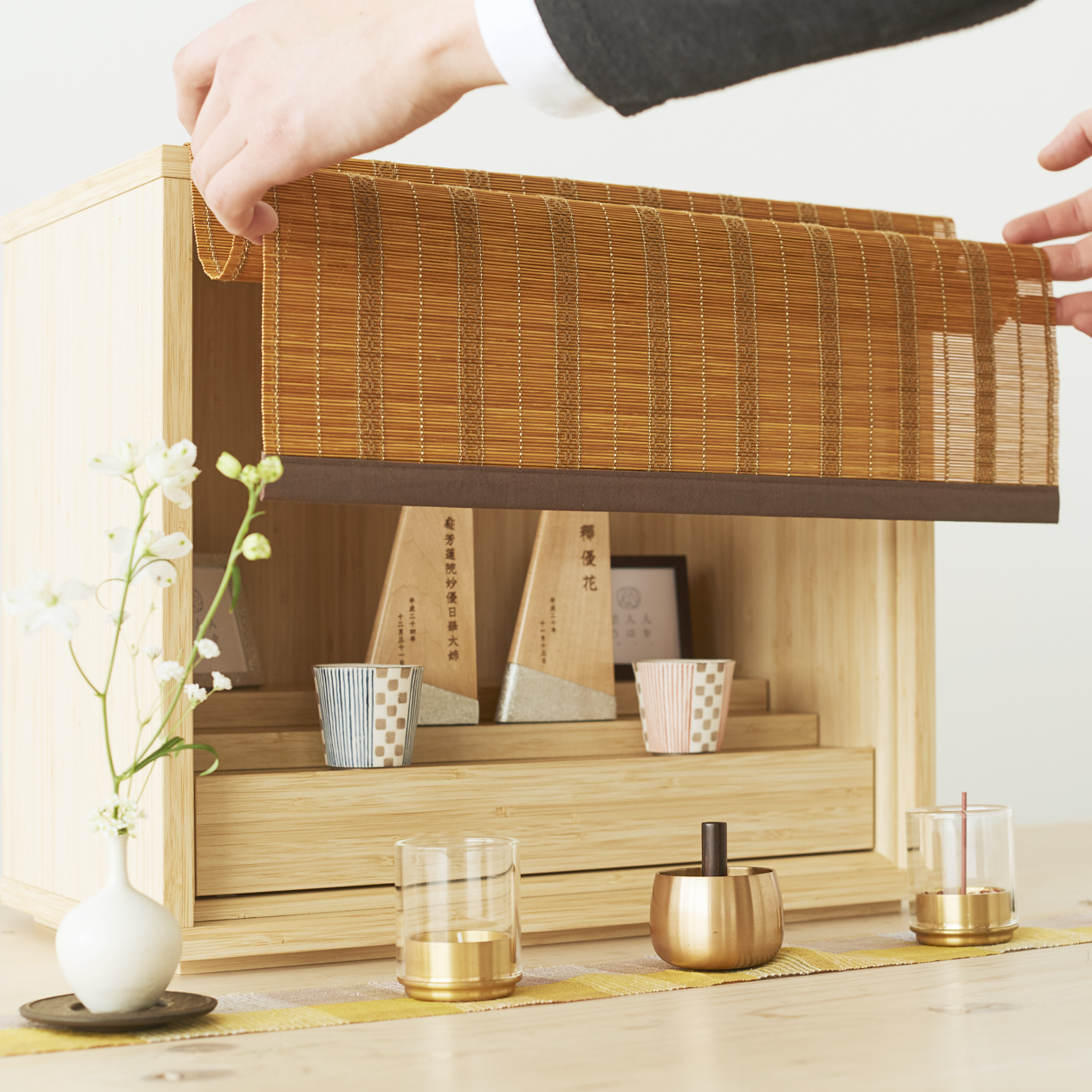 暮らしに寄り添うシンプルな箱型のお仏壇「偲壇」竹のすだれを上げる様子